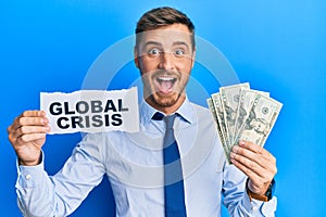 Handsome caucasian business man holding dollars on global crisis celebrating crazy and amazed for success with open eyes screaming