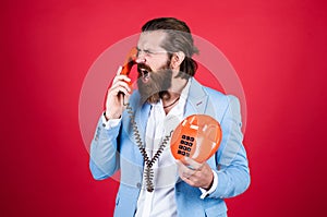 handsome caucasian businessman with trendy hairstyle in jacket speak on vintage phone, anger