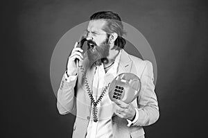 handsome caucasian businessman with trendy hairstyle in jacket speak on vintage phone, anger