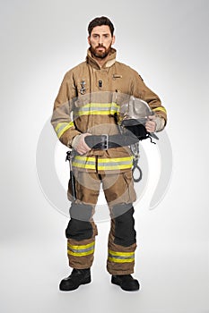 Handsome caucasian firefighter in full gear in studio.