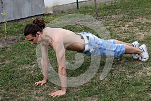 Handsome caucasian guy is working out in the nature.  Gymnastics, healthy lifestyle concept.