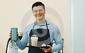 Handsome Caucasian male cafe shop owner smiling with happiness and success, holding tray with coffee glass to serve customers and