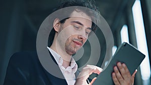 Handsome caucasian male manager using digital tablet, near the business centre texting, scrolling apps. People and