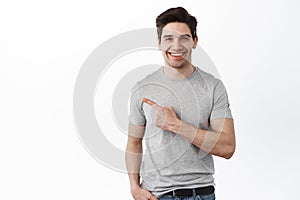 Handsome caucasian male model pointing aside at copyspace. Guy in casual clothes showing advertisement on left side