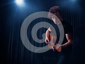 Handsome caucasian male playing an acoustic guitar in the scene