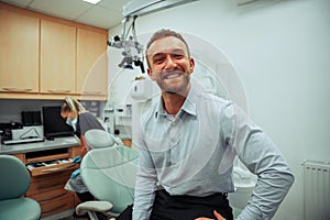 Handsome caucasian male standing in doctors office ready for appointment with female dentist