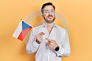 Handsome caucasian man with beard holding czech republic flag smiling happy pointing with hand and finger