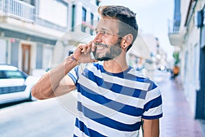 Handsome caucasian man with beard smiling happy outdoors speaking on the phone