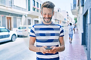Handsome caucasian man with beard smiling happy outdoors using smartphone