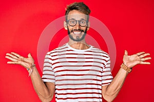 Handsome caucasian man with beard wearing casual clothes and glasses celebrating victory with happy smile and winner expression