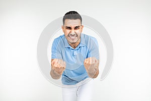 Handsome caucasian man in a blue t-shirt holds fists for good luck on a white studio background