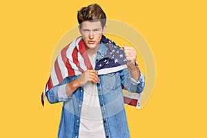 Handsome caucasian man holding united states flag annoyed and frustrated shouting with anger, yelling crazy with anger and hand