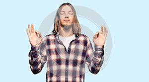 Handsome caucasian man with long hair wearing hipster shirt relax and smiling with eyes closed doing meditation gesture with