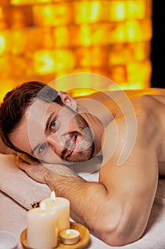 Handsome caucasian man lying on massage table at spa center