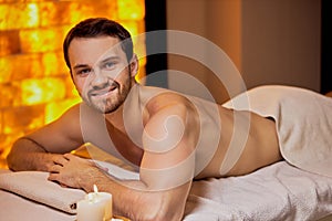 Handsome caucasian man lying on massage table at spa center
