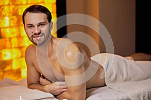 Handsome caucasian man lying on massage table at spa center