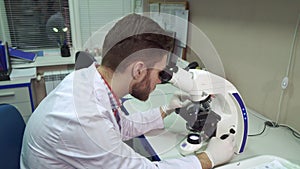 Man moves stage clipse on microscope at the laboratory photo