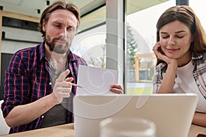 Handsome Caucasian man pointing with a pen on a copy space on the white blank paper sheet while talking by video call sitting at