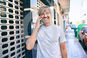 Handsome caucasian man smiling happy outdoors speaking on the phone