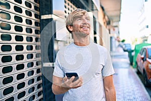 Handsome caucasian man smiling happy outdoors using smartphone