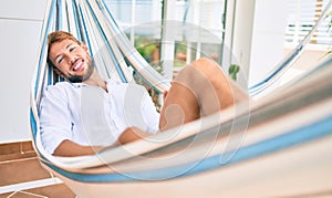 Handsome caucasian man smiling happy resting on a hammock at the terrace