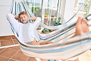 Handsome caucasian man smiling happy resting on a hammock at the terrace