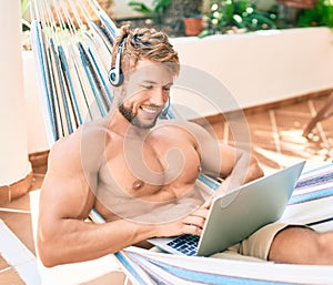 Handsome caucasian man smiling happy resting on a hammock at the terrace working from home wearing call center headset