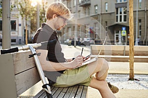 Handsome caucasian man using laptop sitting outdoor in a park. Summer sunshine day. Concept of young business people working