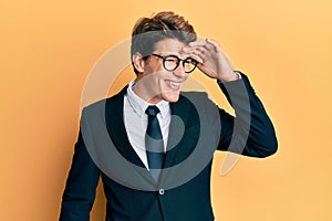 Handsome caucasian man wearing business suit and tie very happy and smiling looking far away with hand over head