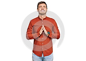 Handsome caucasian man wearing casual clothes begging and praying with hands together with hope expression on face very emotional