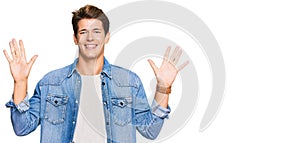 Handsome caucasian man wearing casual denim jacket showing and pointing up with fingers number ten while smiling confident and