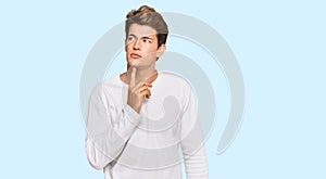 Handsome caucasian man wearing casual white sweater thinking concentrated about doubt with finger on chin and looking up wondering