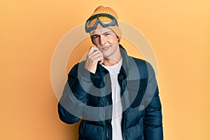 Handsome caucasian man wearing snow wear and sky glasses thinking concentrated about doubt with finger on chin and looking up