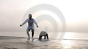 Handsome caucasian man in white clothes doing push ups with jumps up and beautiful smiling woman doing a plunk exercise
