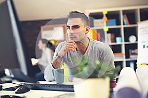 Handsome Caucasian man at work desk facing flat screen computer
