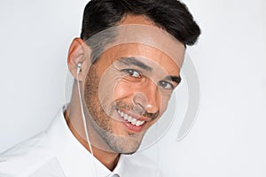 Handsome caucasian young man enjoying his favorite music. Happy stylish smiling man in headphones against gray background.