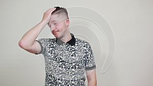 Handsome caucasian young man keeping hand on head, looking aside