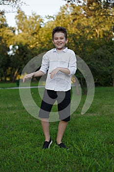 A handsome and charismatic young boy doing pranks and dancing outside in the park. photo