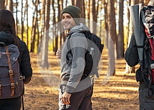 Handsome cheerful guy looking at camera, hiking with friends