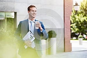 Handsome cheerful man standing near office building