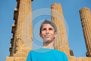 Handsome cheerful teen boy against ancient Greek Temple, Agrigento, Sicily. Famous tourist attraction in Italy.