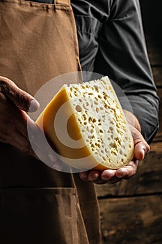 Handsome cheesemaker is checking cheeses in his workshop storage, close up