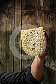 Handsome cheesemaker is checking cheeses in his workshop storage, close up