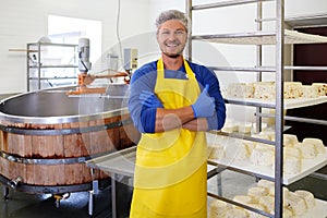 Handsome cheesemaker making curd cheese in his factory.