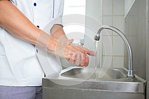 Handsome chef washing hands in commercial kitchen