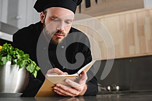 handsome chef writing down new recipe to notebook