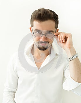 Handsome clever man holding glasses stand against white background. Leaning man in glasses and white shirt, portrait. Close up Smi