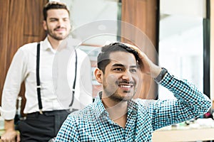 Handsome Client Examining Freshly Cut Hair In Barber Shop