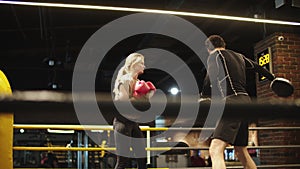 Handsome coach teaching fit girl in sport club. Sport woman boxing at gym