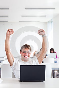 Handsome college student with laptop computer in university library